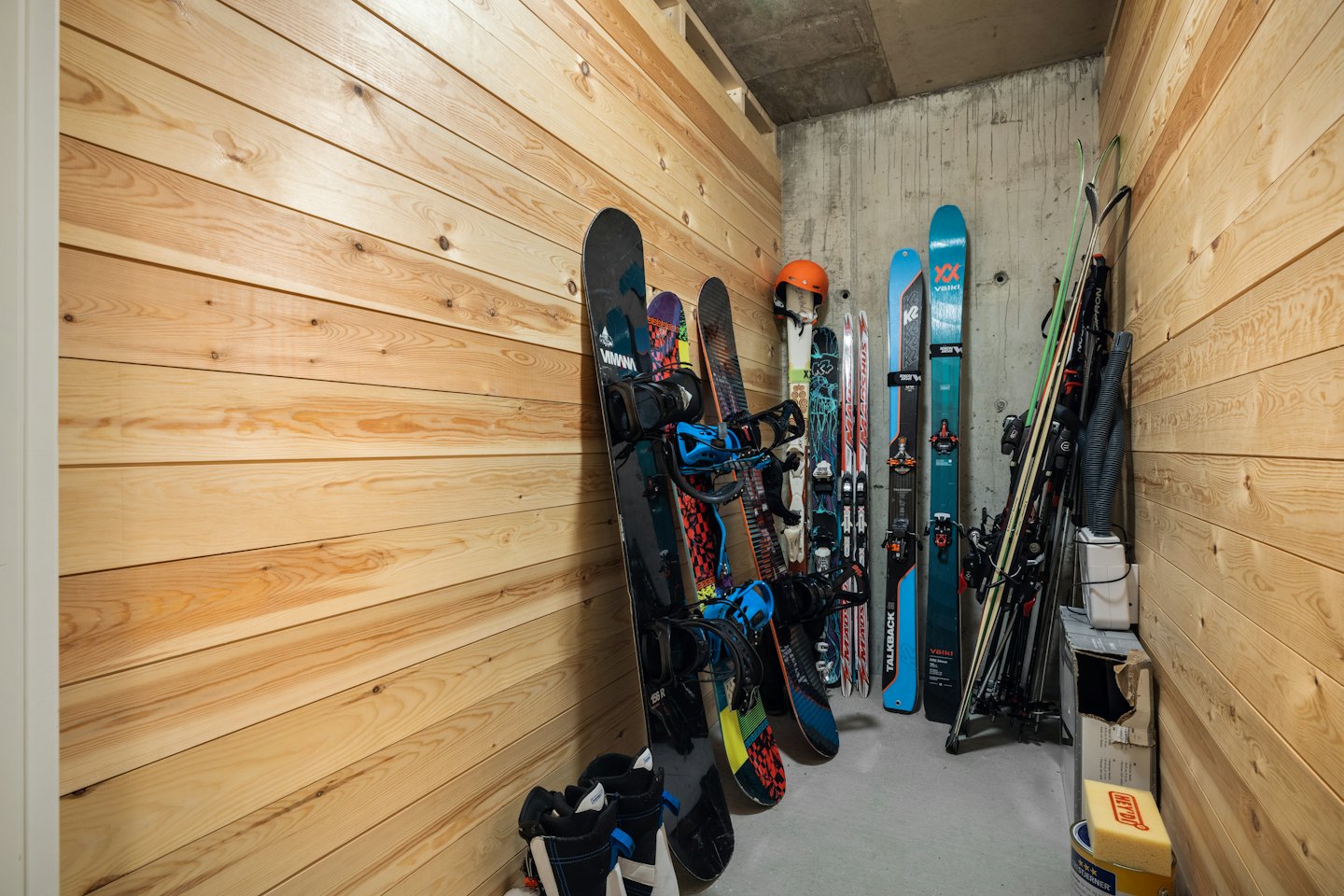 Locale sci con snowboard, sci, scarponi e casco ordinatamente organizzati.