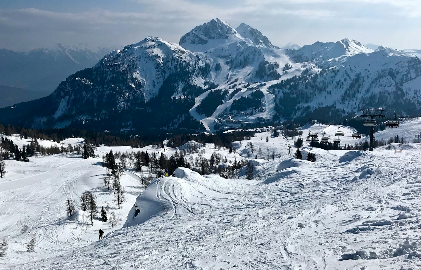 Un singolo sciatore traccia un pendio innevato di montagna.
