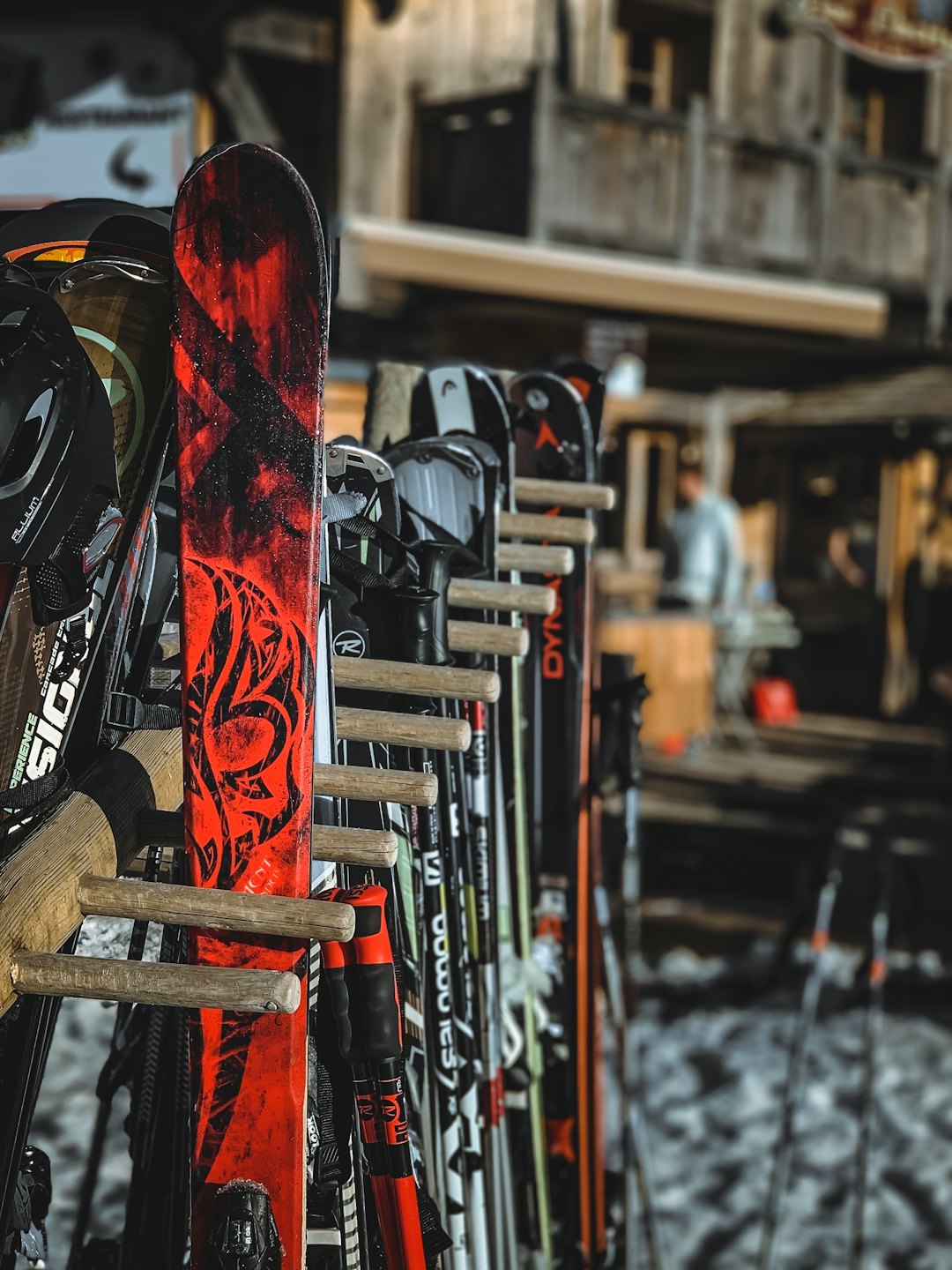 Coppie di sci e bastoncini riposti in un rastrelliere di legno.