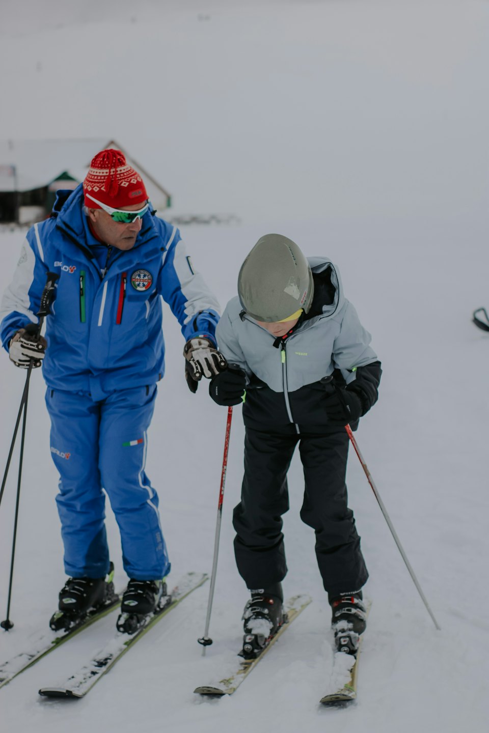 Un maestro di sci aiuta uno studente a fare pratica su una pista innevata.